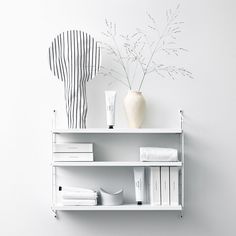 a white shelf with some vases and other items on it