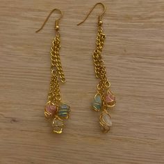 two pairs of gold chain earrings with multicolored glass beads on wooden table top