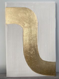 a white and gold striped wall hanging with the letter j on it's side