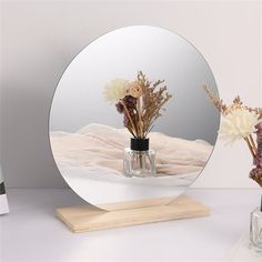 there is a vase with flowers in it and a mirror on the table next to it