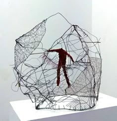 a sculpture is shown on top of a white pedestal with wires in the shape of a human figure