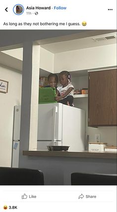 two children standing on top of a refrigerator freezer in a kitchen next to black chairs