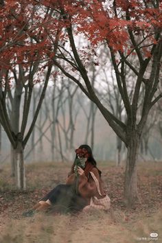 a woman sitting in the middle of a forest