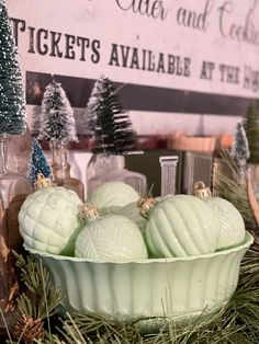 a bowl filled with soap balls on top of a christmas tree covered table next to bottles