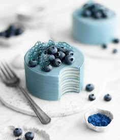 a cake with blueberries on top and frosting next to it, sitting on a plate