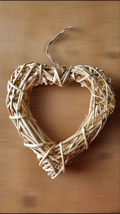 a heart shaped wreath hanging on a wooden table