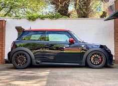 a black mini with red rims parked in front of a building