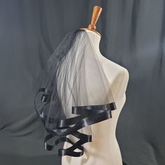 a mannequin wearing a black veil with ribbon around the top and bottom part