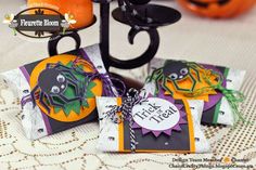 three halloween treat bags sitting on top of a table next to an orange and black pumpkin