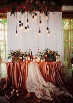 a table with candles and flowers on it is set up in front of a white curtain