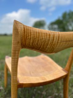 a wooden chair sitting on top of a lush green field