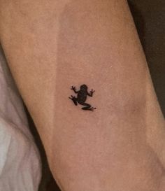 a small frog tattoo on the arm