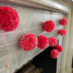 red pom - poms hanging from a fireplace mantel