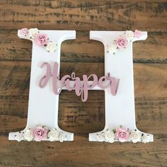 the letter h is decorated with pink flowers and white letters that spell it's happy