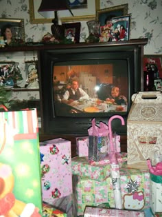 a television sitting on top of a wooden table next to presents and other christmas items