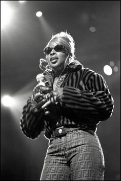 a black and white photo of a woman on stage with her hands in her pockets