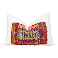 an embroidered pillow with tassels on it