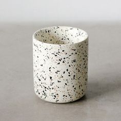 a white and black speckled cup sitting on top of a table