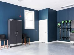 an empty room with blue walls and white doors, two chairs in the foreground and several black lockers on the wall