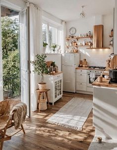 a kitchen with wooden floors and white walls, an open door leading to the outside