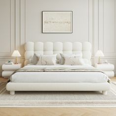 a large white bed sitting on top of a wooden floor next to two nightstands