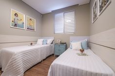 two twin beds in a room with pictures on the wall and wood flooring around them