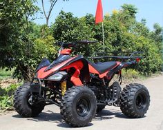 an orange and black four - wheeler parked on the side of a road next to trees