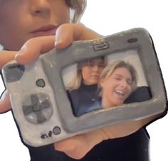 a young boy holding up a small video game device to his face and smiling at the camera