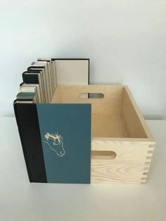 a wooden box filled with books on top of a white table next to a wall