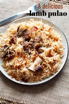 a white plate topped with rice and meat on top of a table next to a fork