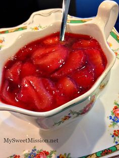 a bowl filled with sliced strawberries sitting on top of a white and green plate