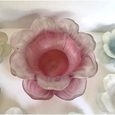 a pink and white flower sitting on top of a table next to other glass flowers