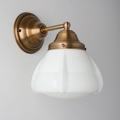 an antique brass wall light with white glass shade