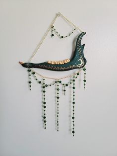 a decorative wall hanging with beads and a bird on it's back, attached to the wall