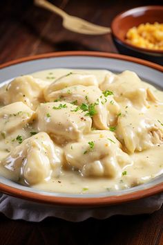 a white plate topped with dumplings covered in gravy next to a bowl of macaroni and cheese