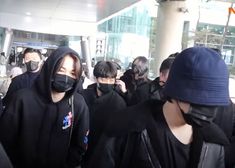 people wearing face masks are walking through an airport