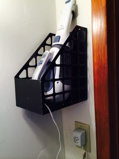 a hair dryer and other items in a holder on the wall next to a plugged outlet