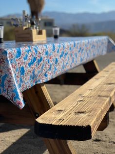 a wooden bench with a blue and red table cloth on it's seat cover