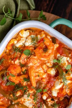 a casserole dish with tomatoes, cheese and herbs