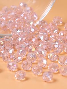 some pink diamonds are sitting on a table next to a pair of tongs and a glass container