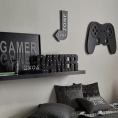 there is a bed with black and white pillows on it, along with two video game controllers mounted to the wall