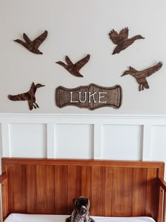 a dog sitting on top of a bed in front of some birds and a name sign