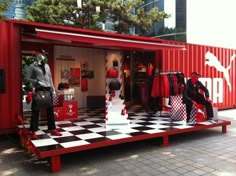 a display in the shape of a shipping container with mannequins dressed in red and black