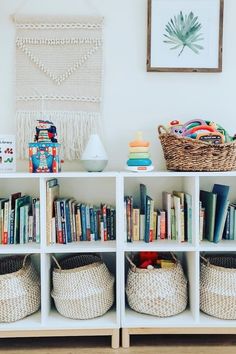 bookshelves with baskets and toys in front of a wall hanging on the wall