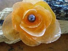 an orange flower with a black pearl in it's center sitting on a piece of wood