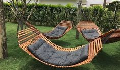 two hammock chairs sitting in the middle of a yard with trees and grass