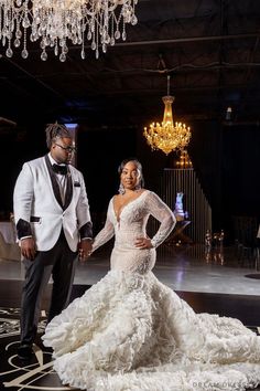 a man and woman standing next to each other in front of a chandelier