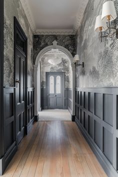 the hallway is decorated with black and white wallpaper, wood flooring and two lamps