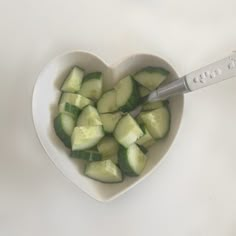 a heart shaped bowl filled with cucumbers next to a thermometer on a table