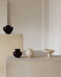 three black and white vases sitting on top of a table